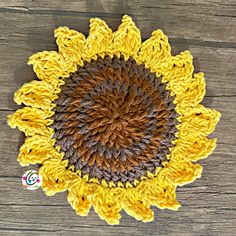 a crocheted sunflower is shown on a wooden surface with a sticker