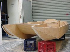 a wooden boat sitting on top of a cement floor next to a red box and some crates