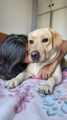 a woman is hugging her dog on the bed