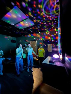 people standing in a room with colorful lights on the ceiling