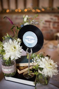 there are flowers in vases and an old record on top of a table with books