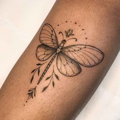 a small dragonfly tattoo on the leg