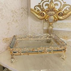 a gold and glass tray sitting on top of a white table next to a mirror