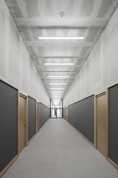 an empty hallway with closed doors and white walls