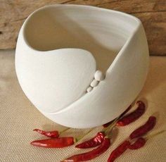 a white bowl sitting on top of a table next to red peppers