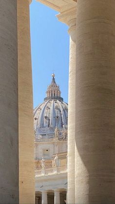 the view from between two columns in front of a building with a dome on top