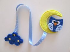 an owl on the moon is hanging from a blue lanyard with a yellow and white ribbon