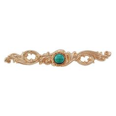 a gold brooch with a green stone in the center