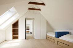 an attic bedroom with white walls and wooden floors, built - in shelving units