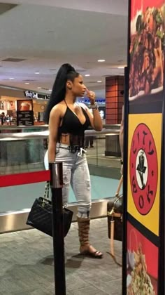 a woman standing in an airport talking on her cell phone and holding a handbag