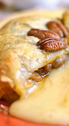 some pecans are sitting on top of a pastry that is covered in cheese and sauce