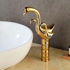 a gold faucet sitting on top of a counter next to a white bowl