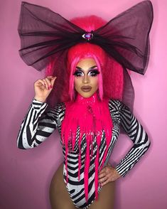 a woman with bright pink hair and makeup is posing for the camera in her costume