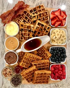 waffles, fruit, and other foods are arranged on a wooden platter