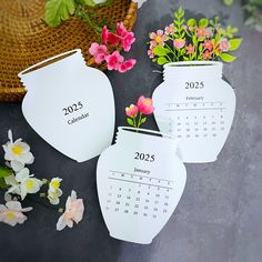 three white vases with flowers in them sitting next to each other on a table