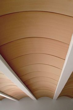 the underside of a wooden ceiling with white walls and wood slats on it's sides