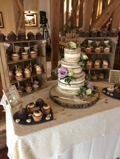 a table topped with lots of cupcakes next to wooden shelves filled with cakes