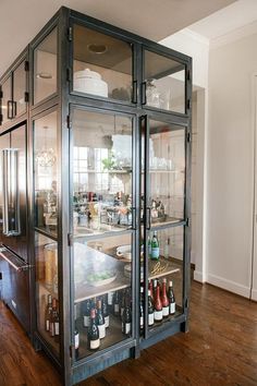 a glass cabinet filled with bottles on top of a hard wood floor