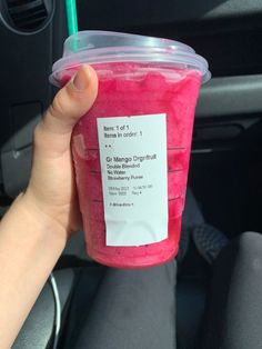 a person holding up a pink drink in their hand