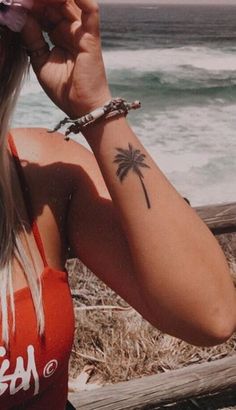 a woman with a palm tree tattoo on her left arm and right arm behind her head