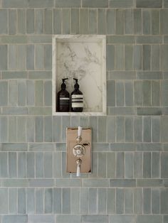 two black and white vases are in the corner of a tiled wall with a square window