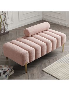 a pink couch sitting on top of a wooden floor next to a rug and magazine rack