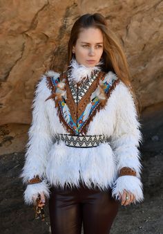 Women's Shamanic Faux fur jacket meticulously handcrafted in the ancient tradition of tribal shamanism, this garment embodies the mystical essence of the wild. Luxuriously adorned with long pile white faux fur, it cascades in soft waves.  Its belted design cinches at the waist, flattering the silhouette while invoking a sense of primal elegance. Each stitch tells a story of connection to the earth and its spirits, making it not just a jacket, but a sacred artifact of mystical power and timeless Fitted White Outerwear For Festival, White Fitted Bohemian Outerwear, Fitted White Bohemian Outerwear, Bohemian Long Sleeve Fur Coat, White Faux Fur Outerwear With Feather Trim, Fur Jackets, Soft Waves, White Faux Fur, Faux Fur Jacket