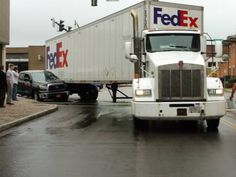 a fedex truck is parked on the side of the road as people walk by