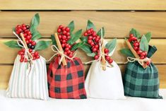 three small bags with red berries and green leaves on them are lined up against a wooden wall