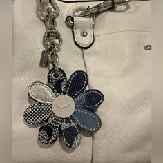 a white purse with a flower on the front and two key chains attached to it