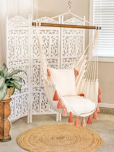 a white hammock with pink tassels on it in front of a window