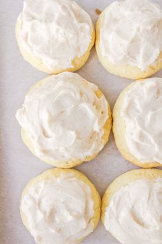 six frosted cookies sitting on top of a baking sheet with icing in the middle