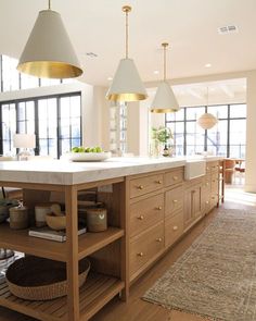 a large kitchen with two hanging lights above the island and an area rug on the floor