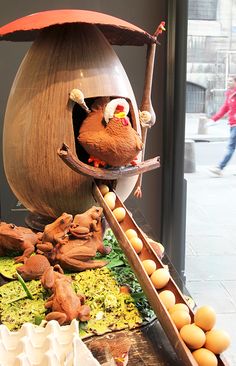 a sculpture of a bird with an umbrella on top of it's head in front of a window