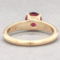 One stamped & tested 14KT yellow gold lady's cast 4-prong gemstone ring with a half round shank with a polished finish. The ring shank measures 3.44 mm wide at the shoulder and tapers to 1.7 mm at the bottom. The ring is size 5 1/4. Identified with markings of "14K". Condition is like new.Containing: One prong set round cabochon cut natural rhodolite garnet, measuring 6.50 x 6.40 x 3.19mm, approximate weight of 1.36ct., clarity is eye clean, medium dark, strong, purple red color, (GIA PR 6/5), c Gold Gia Certified Ruby Ring, Gia Certified Gold Ruby Ring, Gia Certified Gold Ruby Ring With Round Cut, Gia Certified 14k Gold Ruby Ring, Yellow Gold Ruby Ring With Tension Setting, Purple Red Color, Ring Shank, Garnet Ring, Rhodolite Garnet