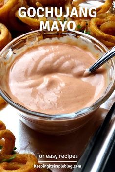 a bowl filled with sauce next to onion rings