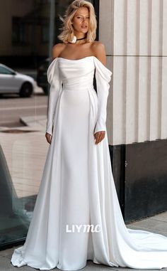 a woman in a white dress is standing on the sidewalk and looking off into the distance