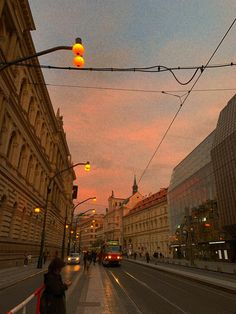 a city street with cars and people walking on the sidewalk at sunset or sunrise time