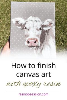 a person holding up a canvas with an image of a cow on it and the words how to finish canvas art with epox resin