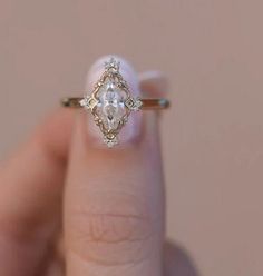 a woman's hand holding a ring with an oval shaped diamond in the middle