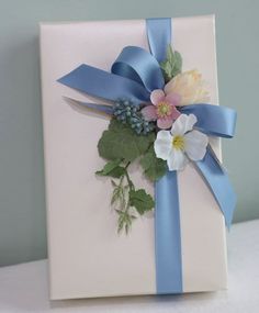 a white box with blue ribbon and flowers on it