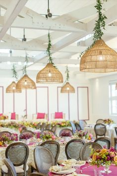 tables and chairs are set up for an event with pink tablecloths, wicker hanging from the ceiling