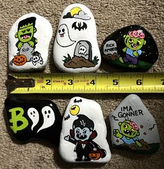 four painted rocks with cartoon characters on them and a measuring tape in front of them