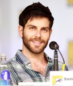 a man sitting at a table with a microphone in front of him and two water bottles behind him