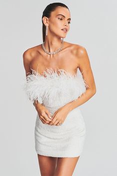 a woman wearing a white dress with feathers on it