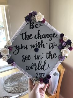 someone holding up a graduation cap that says be the change you wish to see in the world