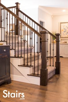 a dog laying on the floor in front of a stair case and wooden handrail