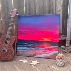 a ukulele sitting on the ground next to a painting