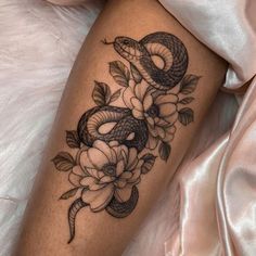 a snake and flowers tattoo on the leg