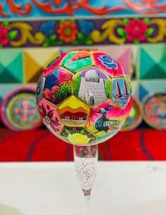 a soccer ball sitting on top of a glass stand in front of colorful wallpaper